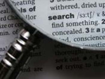 Photo is of a dictionary definition of "Search" magnified. Photographer unknown.